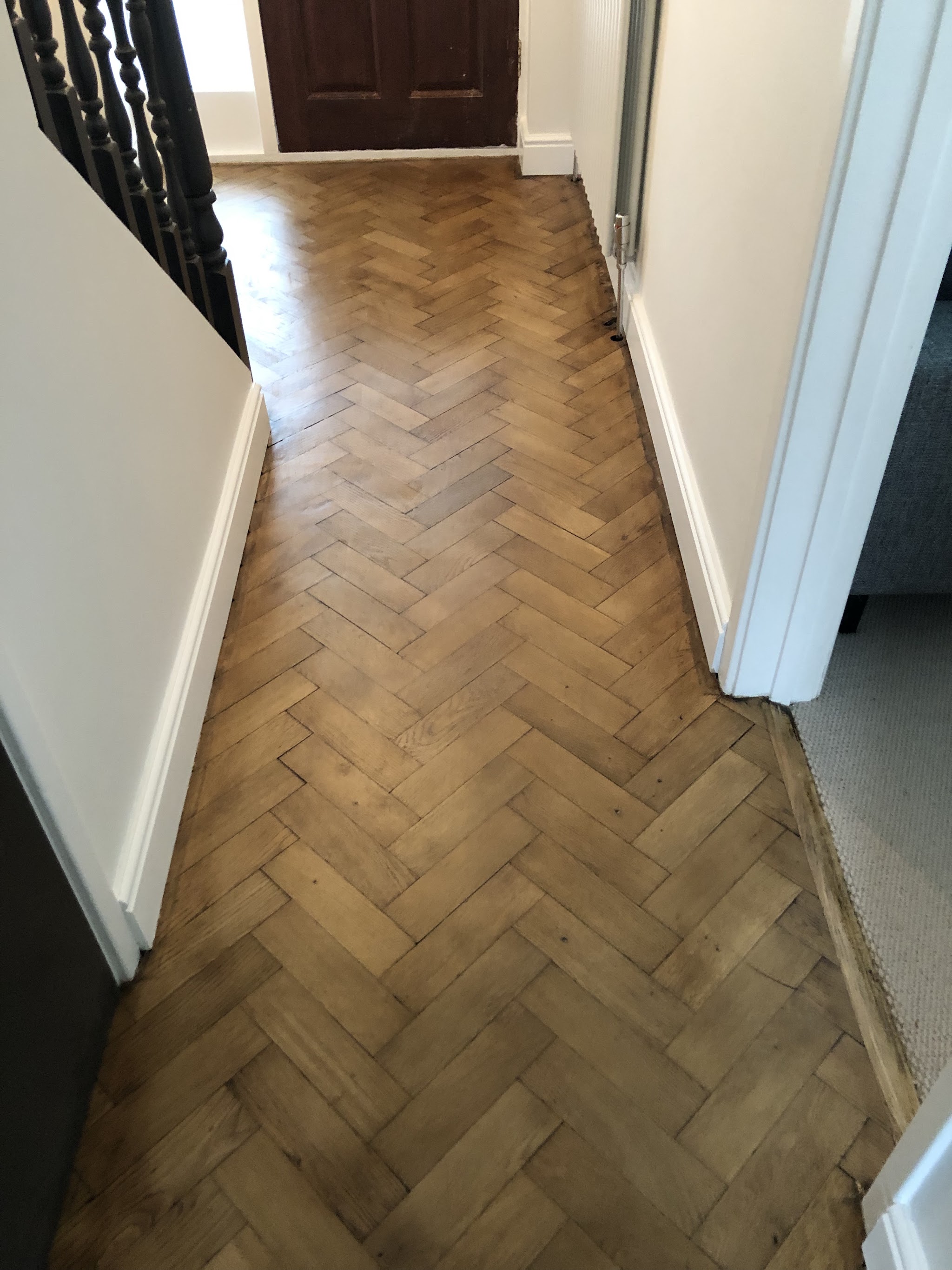 Hallway with herringbone parquet floor and crisp white walls and skirting